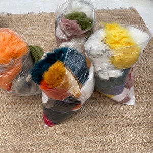 May include: Five plastic bags filled with different colors of faux fur. The bags are on a brown woven rug.