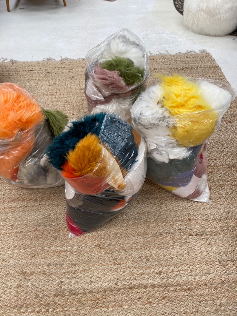 May include: Five plastic bags filled with different colors of faux fur. The bags are on a brown woven rug.