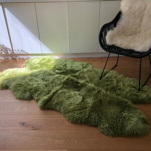 May include: A green and yellow sheepskin rug with long, fluffy fur. The rug is laid out on a wooden floor.