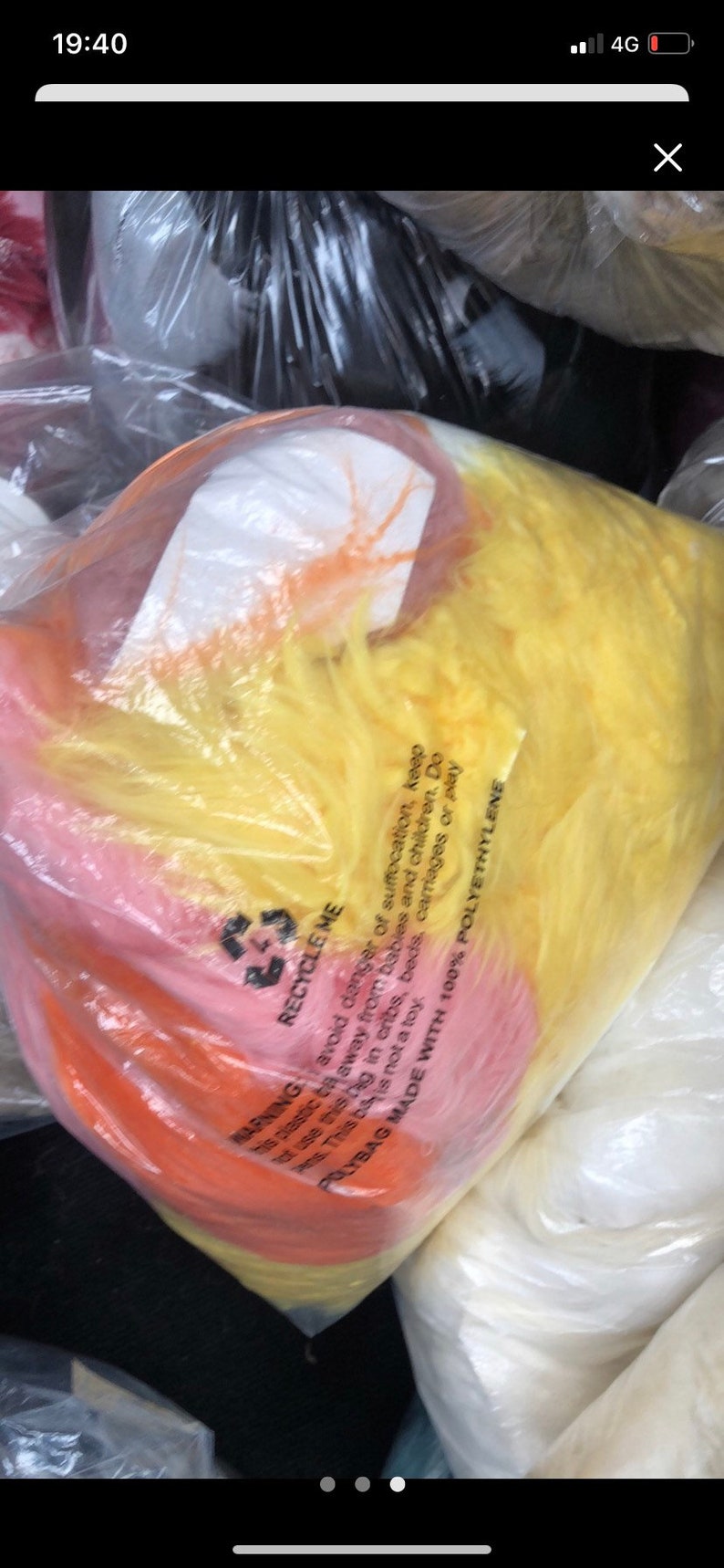 May include: A close-up of a plastic bag filled with colorful, fluffy stuffing. The bag is labeled "Recycle Me" and has a warning to avoid danger of suffocation. The bag is made with 100% polyethylene.