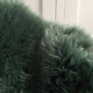 May include: A soft, plush, green sheepskin rug. The rug has a long, dense pile and is perfect for adding a touch of luxury to any room.
