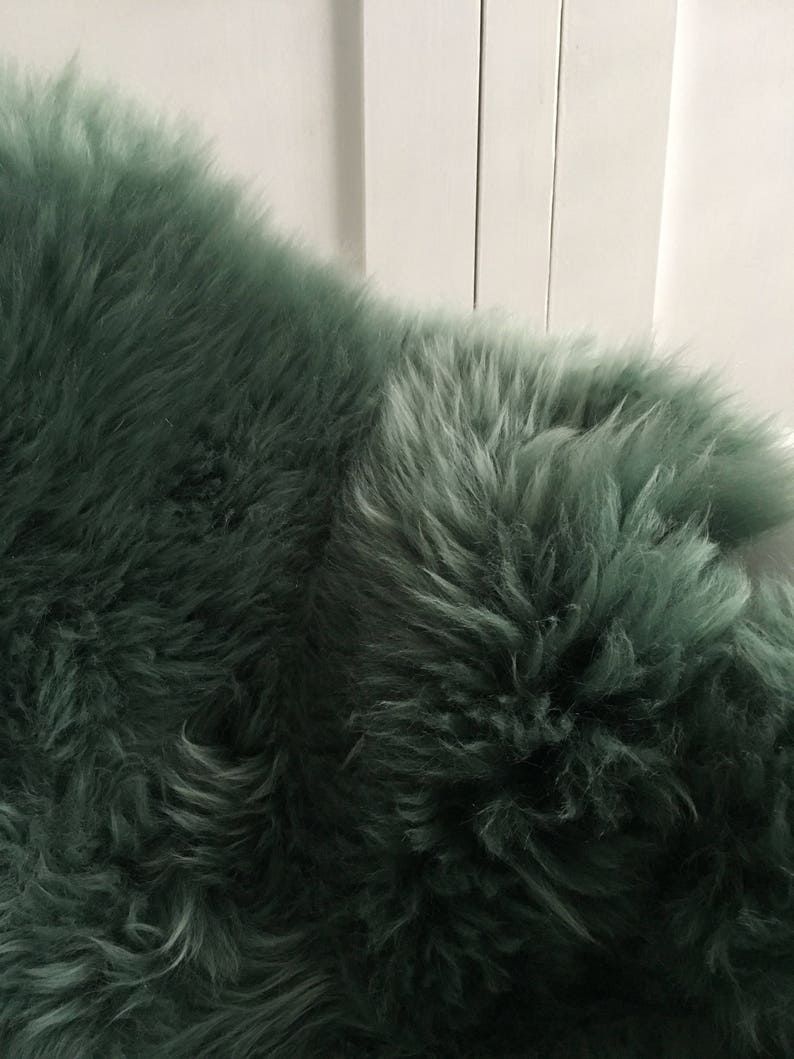 May include: A soft, plush, green sheepskin rug. The rug has a long, dense pile and is perfect for adding a touch of luxury to any room.