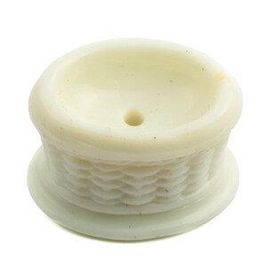 May include: White ceramic bowl with a woven pattern around the base. The bowl has a small hole in the center.