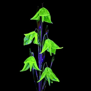 May include: Five neon green glass flowers with bell-shaped blooms and slender stems. The flowers are set against a black background, creating a striking contrast. The stems have a purple hue.