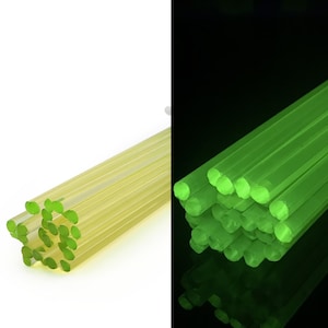May include: A bundle of glow-in-the-dark green plastic rods. The rods are stacked on top of each other and are illuminated in the dark.