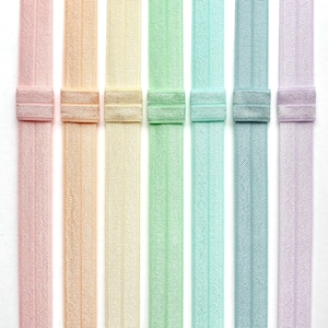Puede incluir: Ocho gomas el&aacute;sticas para el pelo de colores en tonos rosa, melocot&oacute;n, amarillo, verde, azul claro, azul y lavanda. Las gomas para el pelo est&aacute;n dispuestas verticalmente y tienen un patr&oacute;n texturizado.