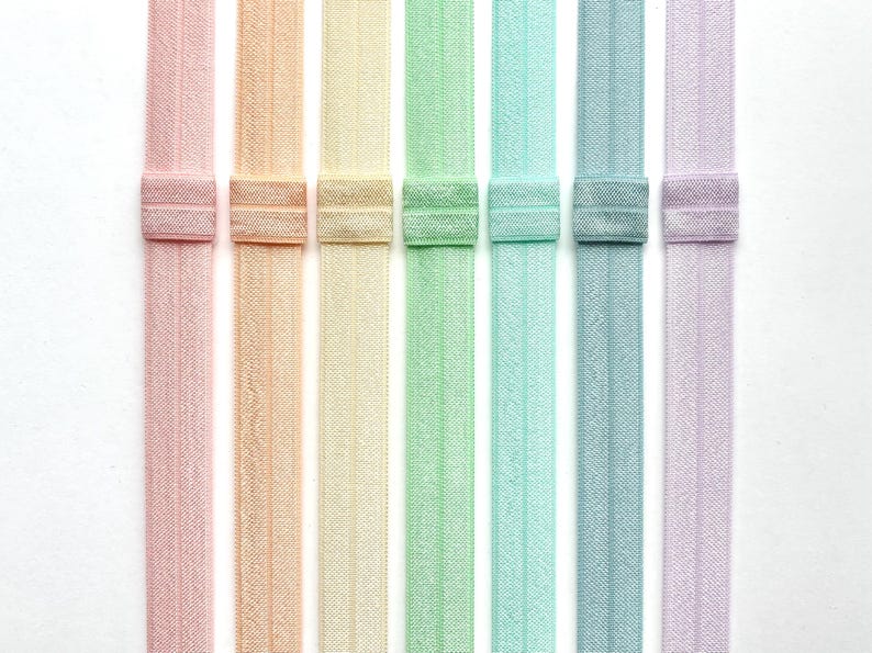 Puede incluir: Ocho gomas el&aacute;sticas para el pelo de colores en tonos rosa, melocot&oacute;n, amarillo, verde, azul claro, azul y lavanda. Las gomas para el pelo est&aacute;n dispuestas verticalmente y tienen un patr&oacute;n texturizado.