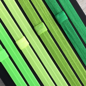 May include: A set of eight green elastic hair ties in various shades of green, from light to dark.