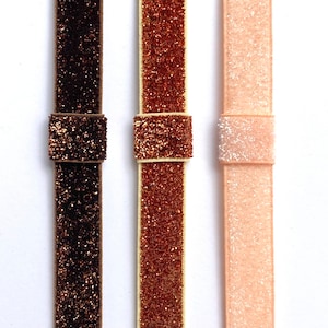 May include: Three different colors of glitter ribbon, brown, copper, and pink.