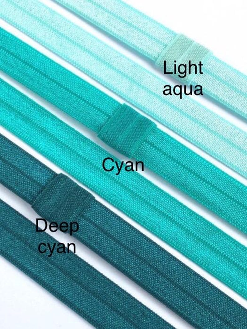 May include: Four different shades of blue elastic hair ties, from light aqua to deep cyan. The hair ties are arranged in a row, with the lightest shade at the top and the darkest shade at the bottom. The hair ties are all made of the same material and have a smooth, shiny finish.