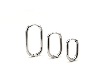 May include: Three silver-toned hoop earrings in an elongated oval shape, arranged in a row from largest to smallest. Each earring features a smooth, polished metallic finish and a hinged closure mechanism at the top for secure fastening.