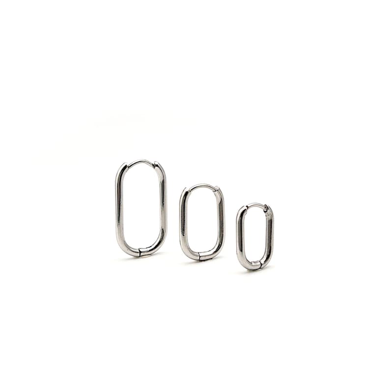 May include: Three silver hoop earrings in different sizes. The earrings are rectangular in shape and have a polished finish.