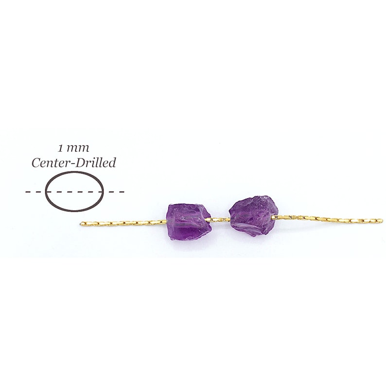 Peut inclure: Deux perles d'am&eacute;thyste violettes brutes enfil&eacute;es sur un fil dor&eacute; fin. Un sch&eacute;ma &agrave; gauche indique un trou perc&eacute; au centre de 1 mm. Les perles pr&eacute;sentent des surfaces irr&eacute;guli&egrave;res et dentel&eacute;es ainsi qu'une teinte violette profonde.