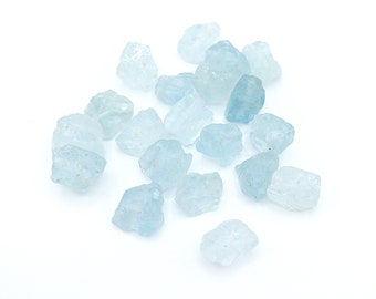 May include: A collection of small, raw, light blue aquamarine crystals with irregular, jagged shapes and translucent surfaces. These natural mineral stones vary in size and display a pale, icy blue color with visible internal textures.