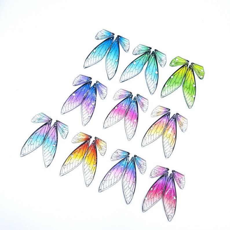 May include: Assortment of colorful iridescent dragonfly wings, each with a unique pattern and color gradient. The wings are made of a translucent material and have a delicate, intricate design.