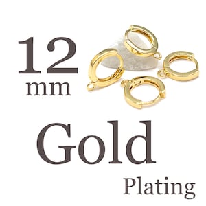 May include: Four gold-plated hoop earring components with small loops for attaching charms. The text 12 mm Gold Plating is displayed next to the jewelry findings, which are arranged in a cluster. These circular metal findings feature a hinged closure mechanism for secure fastening.