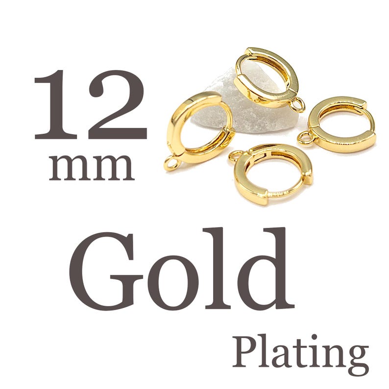 May include: Four gold-plated hoop earring components with small loops for attaching charms. The text 12 mm Gold Plating is displayed next to the jewelry findings, which are arranged in a cluster. These circular metal findings feature a hinged closure mechanism for secure fastening.