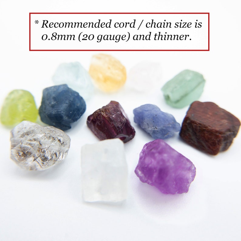 Peut inclure: Une collection de petites pierres pr&eacute;cieuses brutes et multicolores, incluant des pi&egrave;ces transparentes, jaunes, vertes, bleues, violettes et rouge fonc&eacute;. Le texte en haut indique : * Recommended cord / chain size is 0.8mm (20 gauge) and thinner.