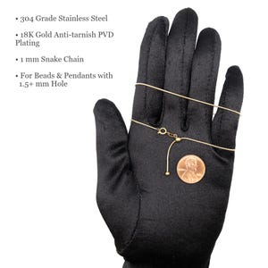 May include: A gold-colored 1 mm snake chain necklace made of 304 grade stainless steel with 18K gold anti-tarnish PVD plating. The chain features an adjustable slider mechanism and is designed for beads and pendants with a hole size of 1.5 mm or larger.
