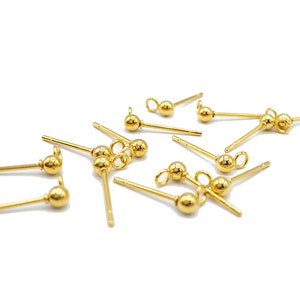 May include: A group of gold-toned earring findings with a small ball at the end of each post. The findings have a loop at the top for attaching a charm or other jewelry.