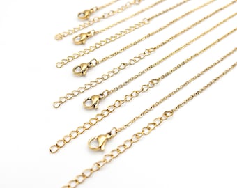 May include: A collection of gold-toned metal necklace chains arranged in a parallel diagonal pattern. Each chain features a delicate link design, a secure lobster claw clasp, and an integrated extender chain with larger circular links.