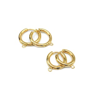 May include: Two pairs of gold hoop earrings with a hinged closure. Each hoop has a small jump ring attached to the bottom.