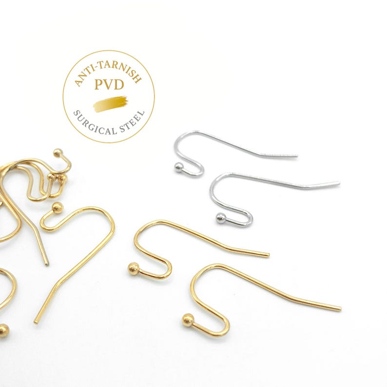 May include: A collection of gold and silver-toned surgical steel earring hooks with a curved design and a small ball at the end. A circular logo is visible with the text ANTI-TARNISH PVD SURGICAL STEEL, indicating the material and finish.