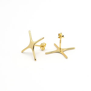 May include: A pair of gold star-shaped stud earrings. The earrings are made of a smooth, shiny metal and have a simple, minimalist design.