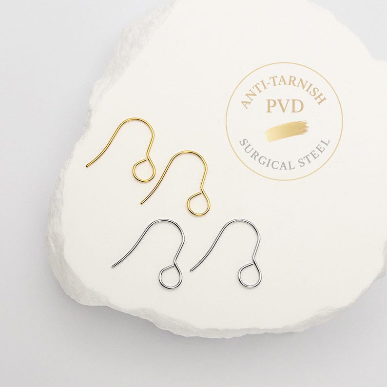 Peut inclure: Deux crochets de boucle d'oreille en m&eacute;tal dor&eacute; et deux en m&eacute;tal argent&eacute; avec un design en fil courb&eacute; et une boucle circulaire &agrave; la base. Un tampon circulaire indique Anti-Tarnish PVD Surgical Steel avec un motif de coup de pinceau dor&eacute;.