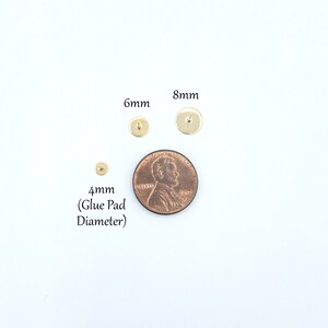 May include: Three gold-colored metal earring studs with flat circular glue pads. The studs are labeled with diameters of 4mm, 6mm, and 8mm. A copper-colored US penny is placed next to the studs for scale, showing the relative size of the components.
