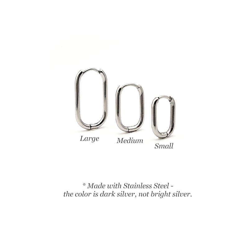 May include: Three stainless steel hoop earrings in different sizes: large, medium, and small. The earrings are oval shaped and have a dark silver finish.