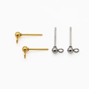 May include: Two gold-toned metal stud earring posts with a small ball top and an attached loop, alongside two silver-toned metal stud earring posts featuring a matching ball top and loop design for jewelry making components.