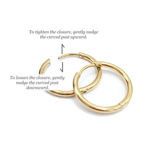 May include: Gold hoop earrings with a hinged closure. Instructions on how to tighten and loosen the closure are included in the image. To tighten, gently nudge the curved post upward. To loosen, gently nudge the curved post downward.