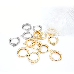 May include: A collection of gold and silver hoop earring findings. The findings have a hinged closure and a jump ring for attaching charms or other jewelry components.