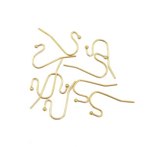May include: A collection of gold-toned metal earring hooks, each featuring a curved wire design with a small decorative ball at the end. These jewelry components are arranged in a scattered pattern, showcasing the smooth finish and consistent shape.