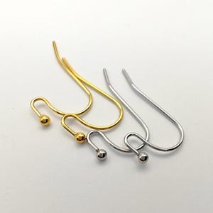 May include: Two pairs of metal earring hooks, one pair in a polished gold tone and one pair in a polished silver tone. Each hook features a curved wire design with a small spherical bead at the end, designed for attaching jewelry components.