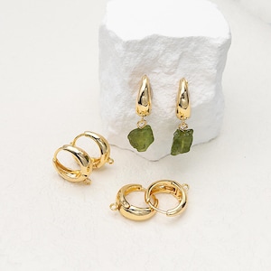 May include: Gold-colored hoop earrings with a polished finish. Two pairs of small hoops and a pair of larger hoops with a green, raw-cut gemstone dangle from the bottom. The earrings are displayed on a white surface.