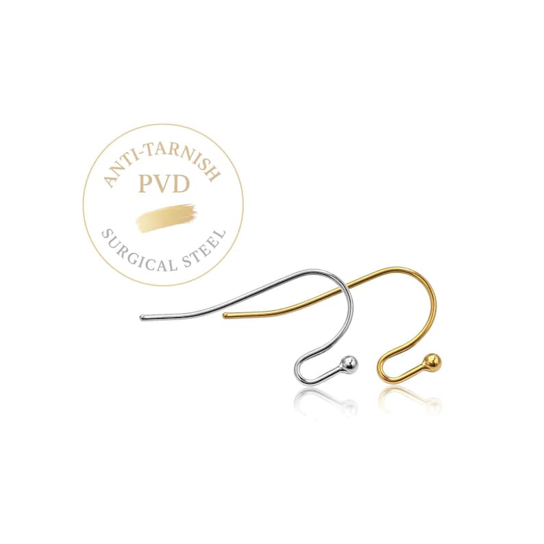 May include: Two earring hooks, one silver-toned and one gold-toned, featuring a curved wire design with a small ball at the end. A circular emblem above the hooks displays the text ANTI-TARNISH PVD SURGICAL STEEL with a gold brush stroke graphic.