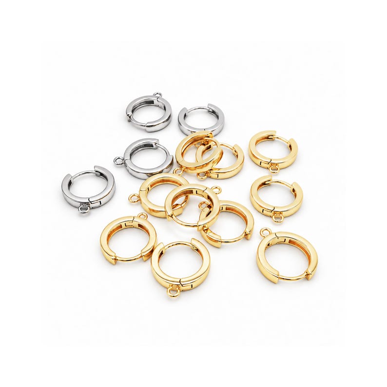 Op de afbeelding: Een verzameling kleine, ronde oorringen met een scharniersluiting en een klein oogje aan de onderkant voor het bevestigen van bedels. De set bevat diverse exemplaren met een gepolijste zilverkleurige en goudkleurige afwerking.