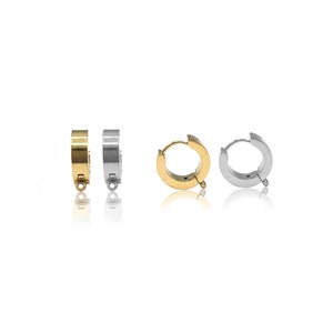 May include: Four small hoop earrings with attached loops for charms. Two earrings are gold-toned and two are silver-toned. The hoops feature a hinged closure mechanism, with two shown from the side and two shown from the front, displaying the circular shape and the small connector ring at the bottom of each piece.