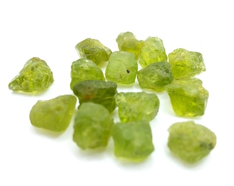 Peut inclure: Une collection de petites pierres précieuses péridot brutes d'une couleur vert citron translucide et vibrante. Ces spécimens minéraux naturels présentent des formes irrégulières et dentelées ainsi que des surfaces brutes non polies.