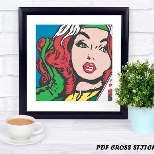 May include: A cross stitch pattern featuring a pop art style illustration of a woman with red hair and green clothing. The image is in a black frame and is ready to be stitched.