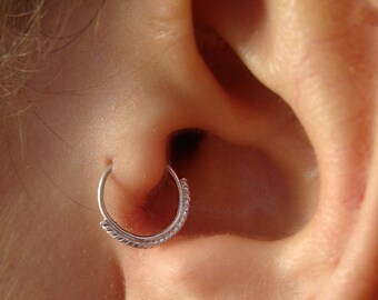 Könnte beinhalten: Nahaufnahme eines Ohres mit einem silbernen Ohrring. Der Ohrring ist ein einfacher, dünner Ring mit leicht strukturierter Oberfläche.