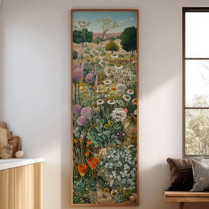 May include: A vertical framed artwork depicting a vibrant field of wildflowers in a landscape setting. The artwork features a variety of colorful blooms, including purple alliums, white daisies, and orange flowers, set against a backdrop of rolling hills and trees.