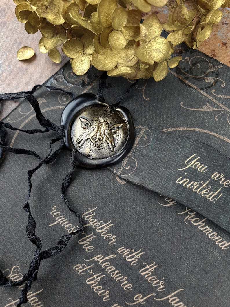 May include: A black and gold wedding invitation with a wax seal featuring a stylized bird design. The invitation reads "You are invited! By Richmond together with their family requests the pleasure of your presence at their wedding."