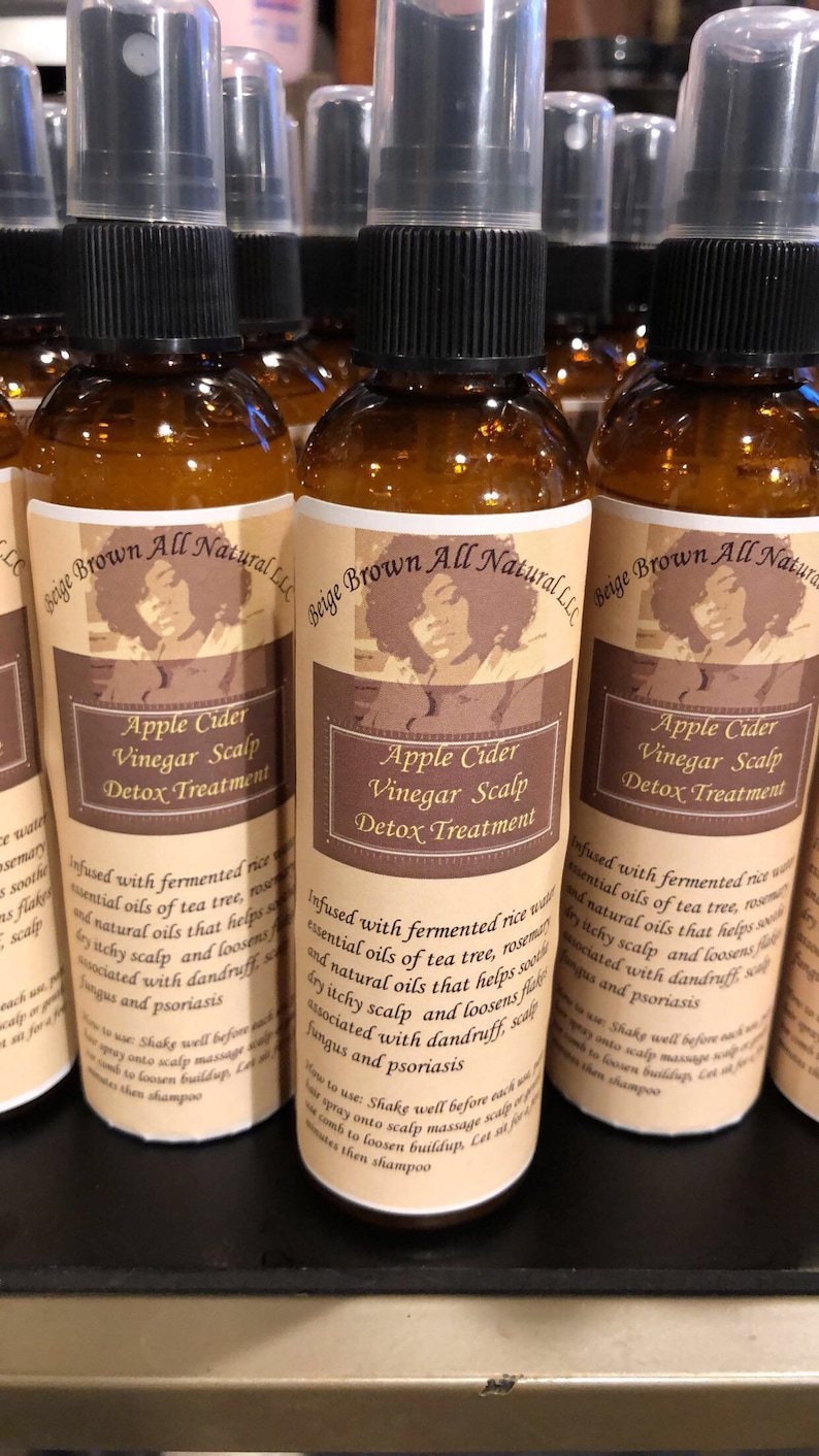 Puede incluir: Tres botellas de vidrio marr&oacute;n con tapas de pulverizador negras y etiquetas que dicen "Beige Brown All Natural LLC" y "Apple Cider Vinegar Scalp Detox Treatment". Las etiquetas tambi&eacute;n incluyen un dibujo de una mujer con cabello rizado.