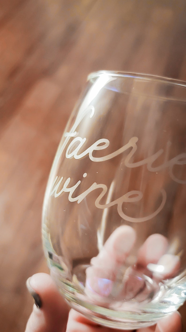 May include: A clear glass wine glass with the words "Fairy Wine" etched into the side.