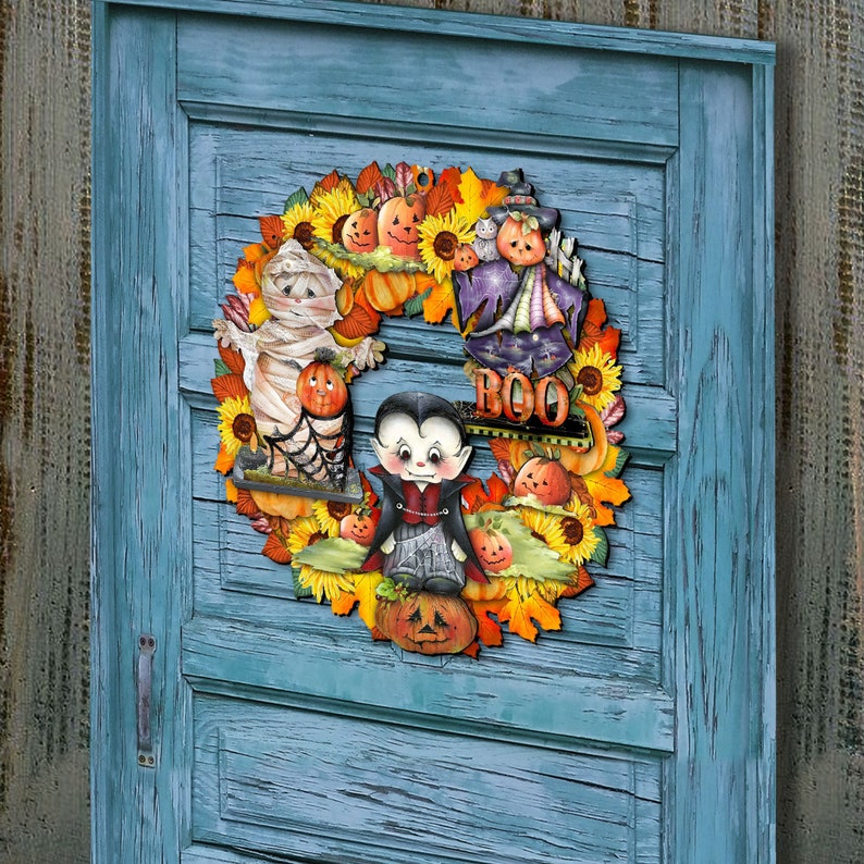 Peut inclure: Une couronne d'Halloween avec une vari&eacute;t&eacute; de personnages effrayants, dont une momie, un vampire et une sorci&egrave;re. La couronne est d&eacute;cor&eacute;e de tournesols, de citrouilles et de feuilles. La couronne pr&eacute;sente &eacute;galement le mot "BOO" au centre.
