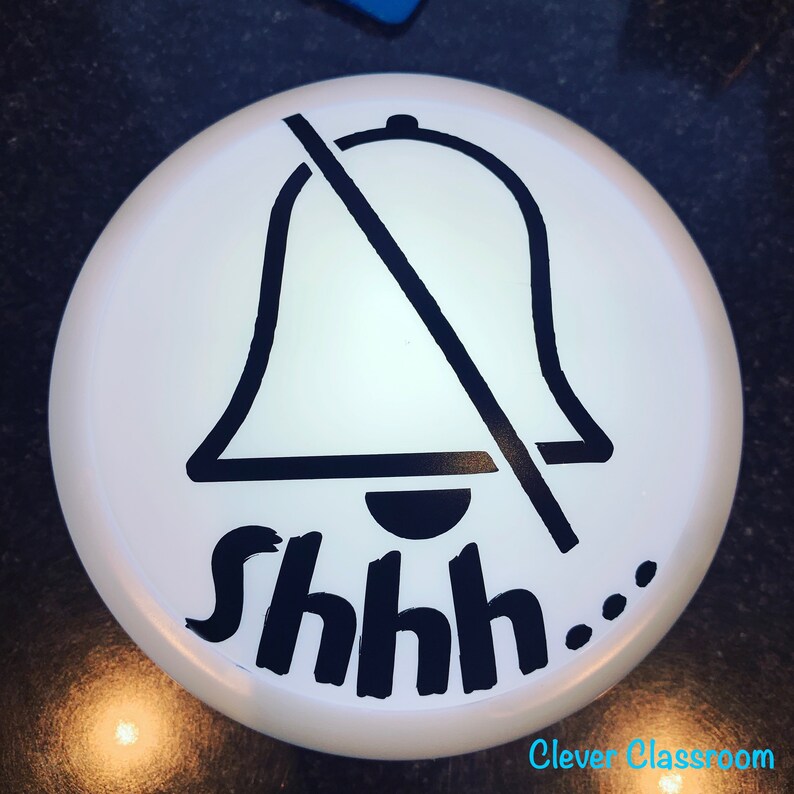 May include: White round sign with a black bell crossed out and the text "Shhh..." in black.