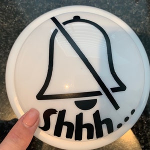 May include: White round button with a black bell icon crossed out and the text "shhh..." printed below.